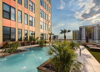 A pool with a waterfall in front of a building with a balcony.